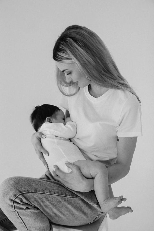A mum wearing jeans and white t-shirt  with baby 