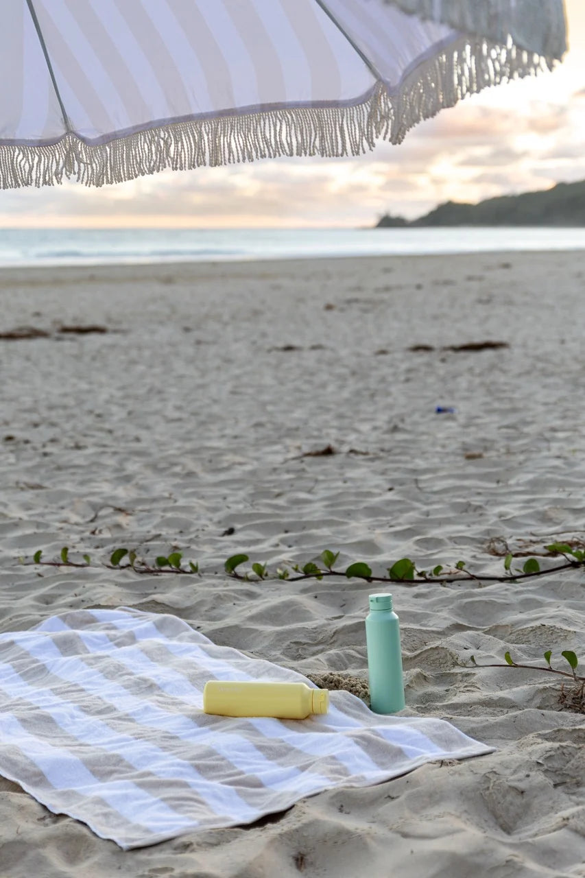 Worthy mint and butter yellow drink bottles on beach