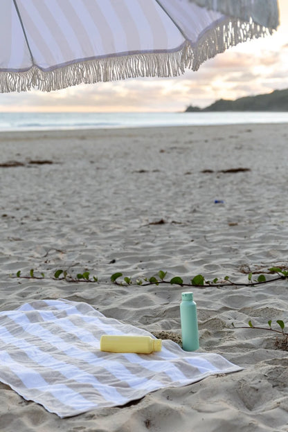 Worthy mint and butter yellow drink bottles on beach